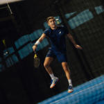 Athlete wearing the Combi Deal Navy padel clothing set, demonstrating movement and flexibility while playing on the court, showcasing both style and performance.