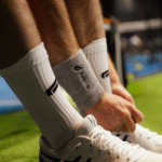 Athlete adjusting the grey Performance Wristbands, showcasing their comfort and functionality for on-court performance.