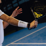 Athlete wearing white Performance Wristbands during a game, providing support and comfort while using the racket on the padel court.
